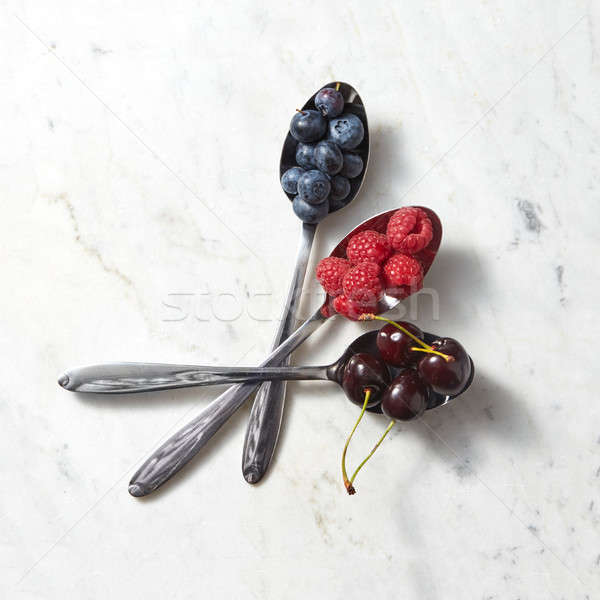 Mix of fresh organic blueberries, cherries, raspberries in the spoons on a white marble background.  Stock photo © artjazz