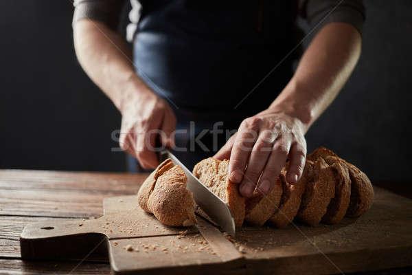 Male hands slicing home-made bread on the wooden board Stock photo © artjazz
