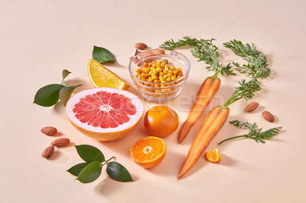Natural freshly picked fruits- citrus fruits, carrots, sea buckthorn berries on an orange paper. Stock photo © artjazz