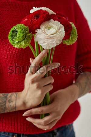 Beautiful girl in a red sweater with flowers in hands on a white background Stock photo © artjazz