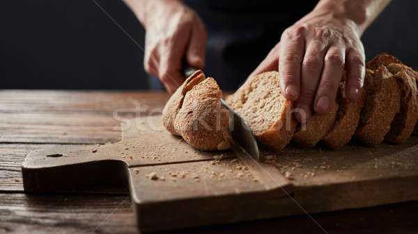 man cutting fresh bread on wooden table Stock photo © artjazz