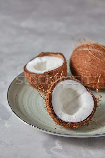 The halves of tropical coconut with whole coconut on a plate on  Stock photo © artjazz