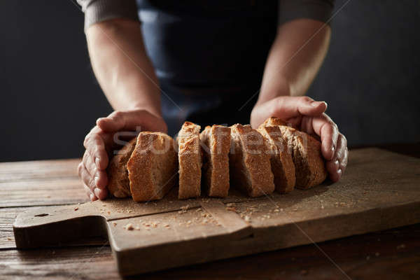 Fresh slice home bread in male's hands on wooden table Stock photo © artjazz