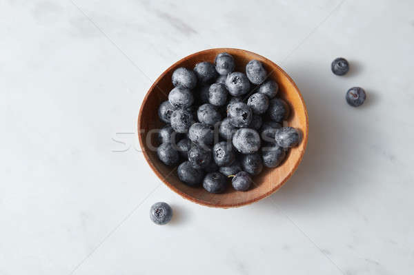 Organic freshly picked blueberry in a wooden bowl on a white kitcen table. Copy space. Stock photo © artjazz