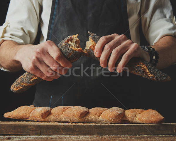 baker man holding fresh halves of a baguette Stock photo © artjazz