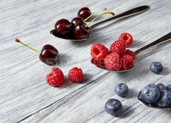 Delicious juicy berries on a spoon gray wooden background. Flat lay. Concept of vegetarian eating. Stock photo © artjazz