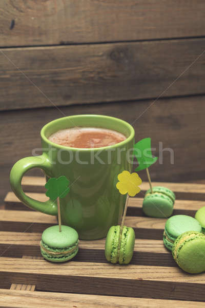 Hot cocoa in green cup and green macaroon cookies scattered on t Stock photo © artsvitlyna