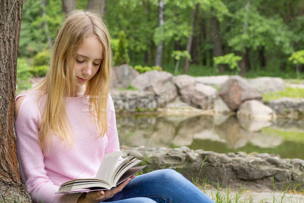 Cute teenage-girl reading a book in the city park Stock photo © artsvitlyna