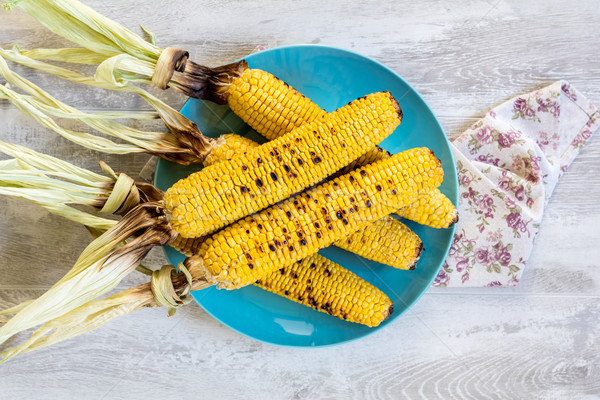 Corn baked in olive oil and salt on blue dish on light surface Stock photo © artsvitlyna