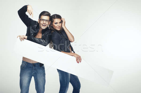 Fashionable happy pretty couple holding white board Stock photo © arturkurjan