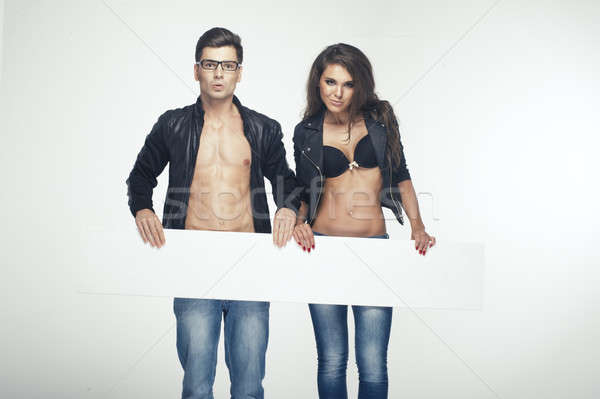 Fashionable happy pretty couple holding white board Stock photo © arturkurjan
