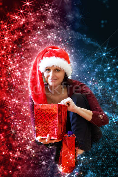 Beautiful middle age woman in red party santa hat sitting with gifts, with abstract background Stock photo © artush