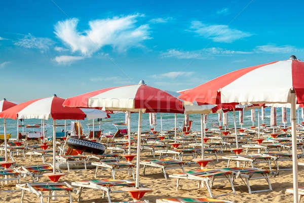 red and white umbrellas and sunlongers on the sandy beach Stock photo © artush