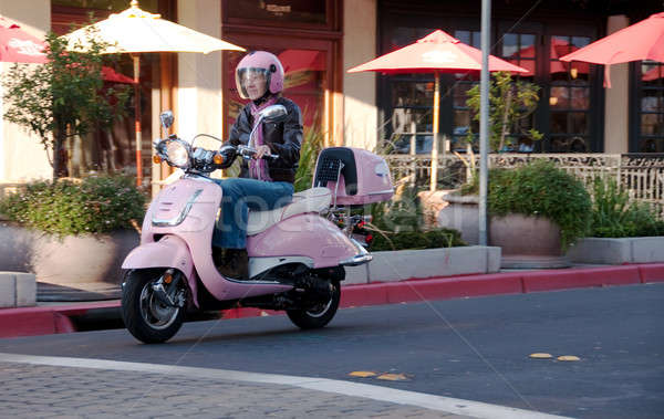 sixty year old lady riding on the city streets in her scooter Stock photo © aspenrock