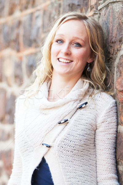 Smiling happy young blonde woman next to natural stone wall Stock photo © avdveen