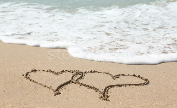 Drawing in sand by ocean of two hearts Stock photo © backyardproductions