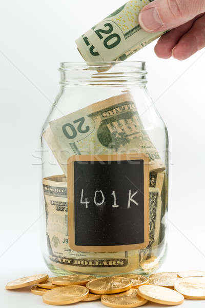 Hand inserting money into saving jar or bank Stock photo © backyardproductions