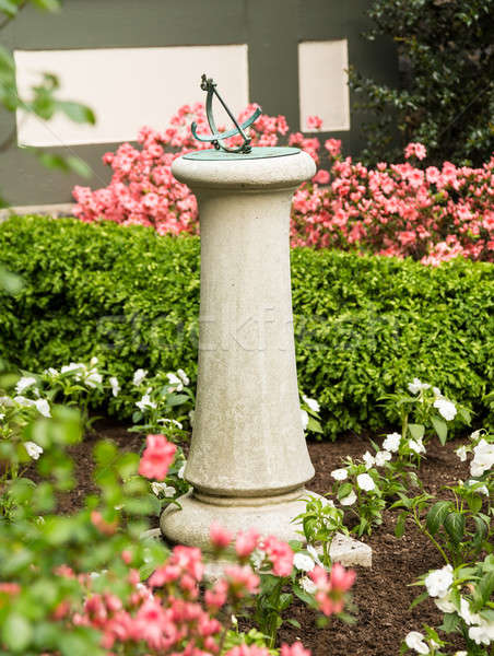 Concrete stone sundial in flower bed Stock photo © backyardproductions