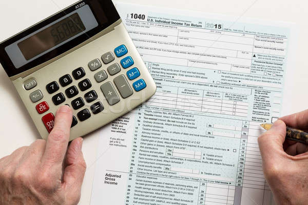 Pen and calculator on 2015 form 1040 Stock photo © backyardproductions
