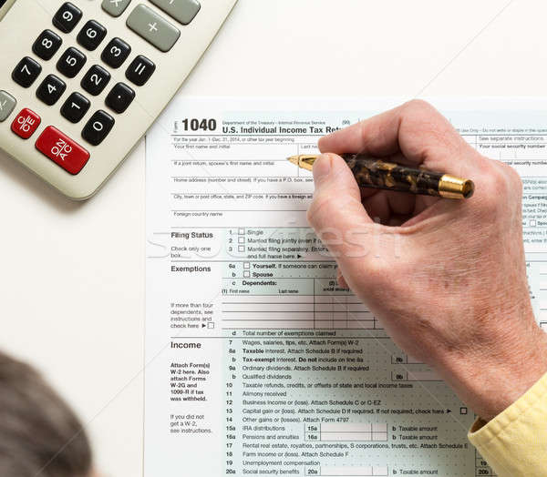 Pen and calculator on 2014 form 1040 Stock photo © backyardproductions