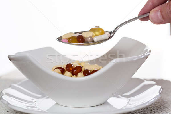 Spoon of vitamins over bowl of tablets Stock photo © backyardproductions