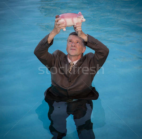 Senior man holding piggy bank above water Stock photo © backyardproductions