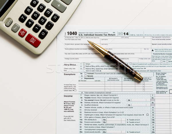Pen and calculator on 2014 form 1040 Stock photo © backyardproductions
