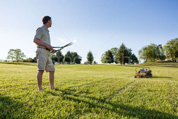 Senior man cutting grass with shears Stock photo © backyardproductions