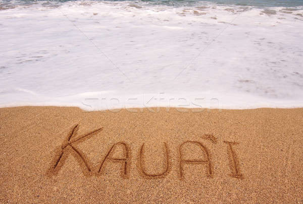 The word Kauai written into the sand in front of surging tide Stock photo © backyardproductions