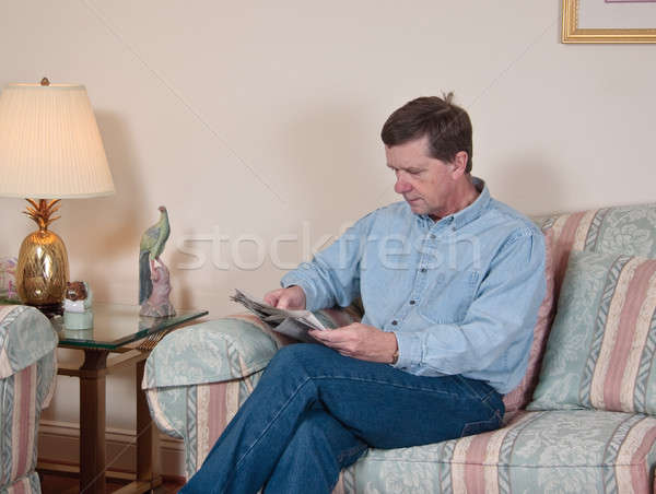 Middle-aged man relaxes on sofa in modern living room Stock photo © backyardproductions