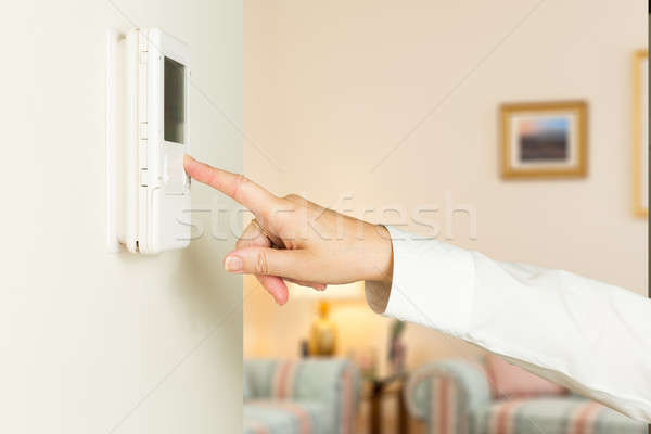 Caucasian lady pressing modern thermostat Stock photo © backyardproductions