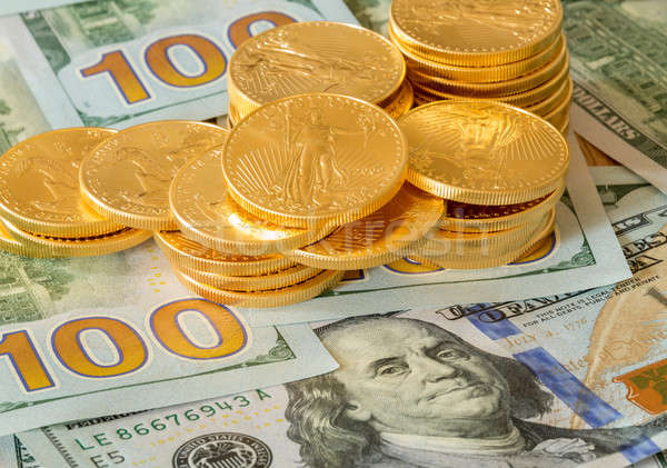 Stock photo: Gold coins stacked on new design 100 dollar bills