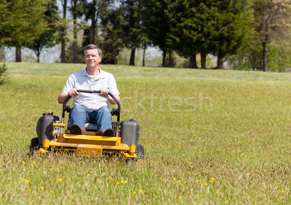 Senior man on zero turn lawn mower on turf Stock photo © backyardproductions