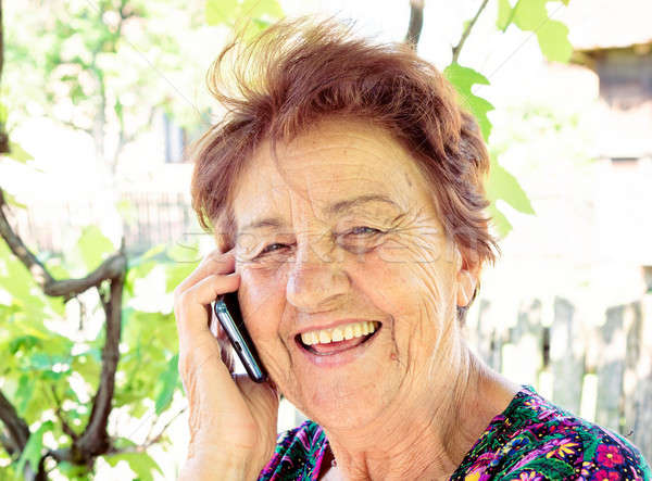 Boldog öreg hölgy mobiltelefon mosoly arc technológia Stock fotó © badmanproduction