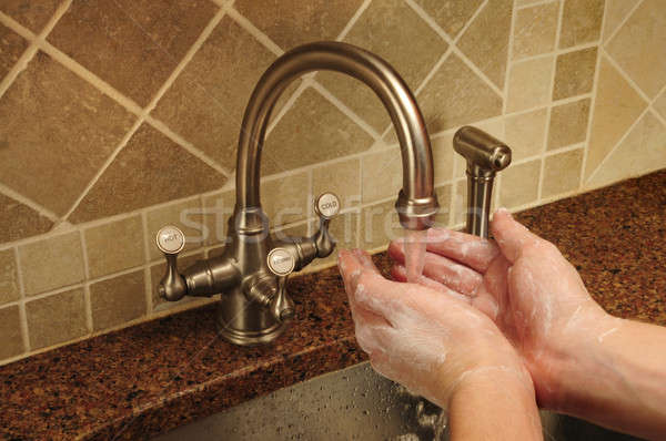 Soapy hand washing under flowing water out of a faucet Stock photo © Balefire9