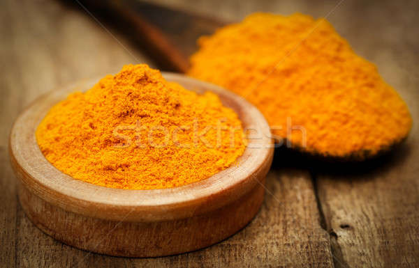 Ground turmeric in a bowl and spon Stock photo © bdspn