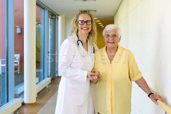 Kind Nurse Assisting Old Patient at the Hallway Stock photo © belahoche