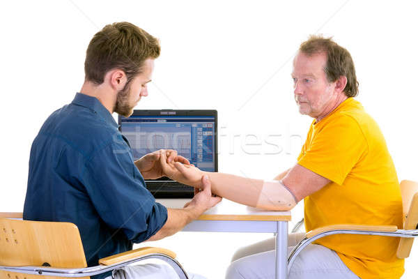 Medical professional works with patient in yellow. Testing function of arm-prosthesis. Stock photo © belahoche