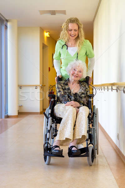 Nurse Assisting Elderly on Wheelchair at Corridor Stock photo © belahoche