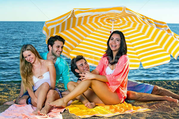 Stock photo: Two young couples on a beach under an umbrella