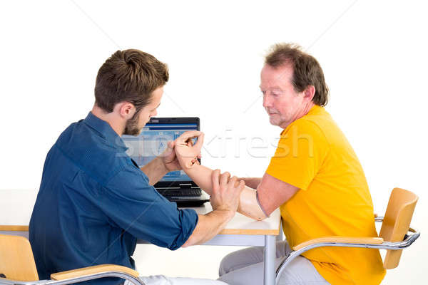 Amputee works with medical professional at table. Testing function of arm-prosthesis with patient. Stock photo © belahoche