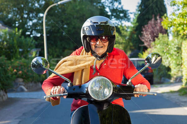 Idős hölgy lovaglás moped visel sisak Stock fotó © belahoche