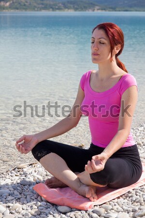 Woman meditating on a lakeshore. Stock photo © belahoche