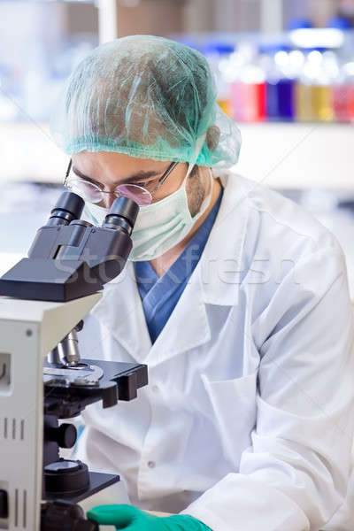 Scientist in a lab looking down a microscope.  Stock photo © belahoche