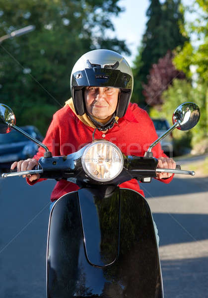 Stock photo: Senior woman riding a scooter