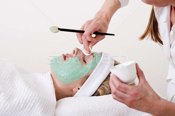 Beautician retouching a blond woman thalasso facial mask.  Stock photo © belahoche