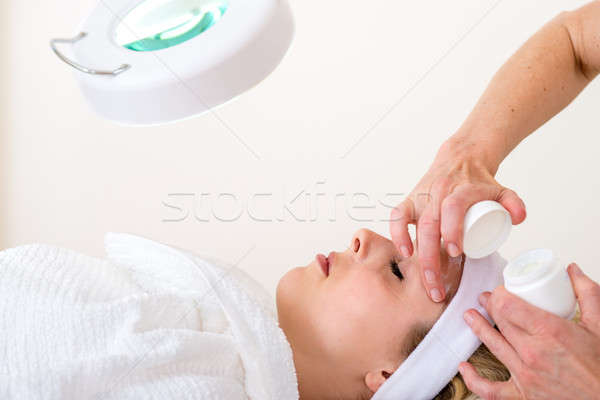 Beautician applying cream on the face of a woman.  Stock photo © belahoche