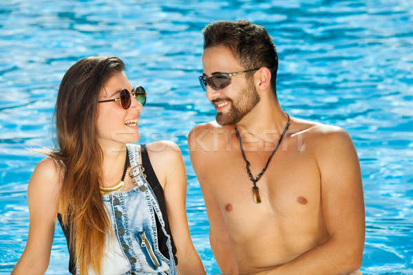 Young couple chatting at the side of a pool Stock photo © belahoche