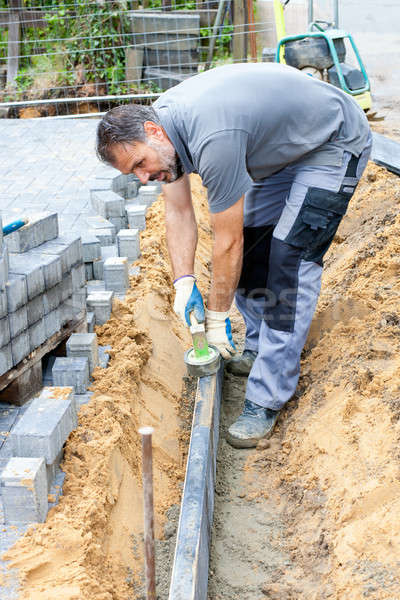 Stock photo: Worker puts border stones.