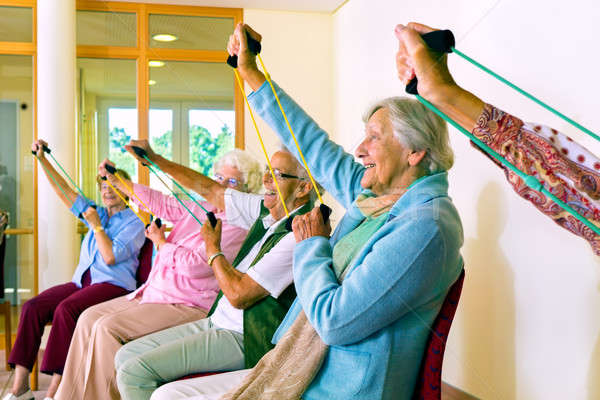 Women in chairs using stretching bands Stock photo © belahoche